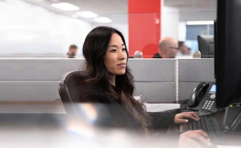 Femme travaillant sur un ordinateur à un bureau représente la main d'oeuvre de qualité, l'attrait du talent international et la croissance du capital humains que Laval économique désire placer à l'avant-plan