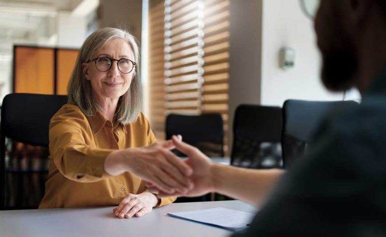 Une femme entrepreneure serrant la main à un jeune homme, illustrant la relève entrepreneuriale.